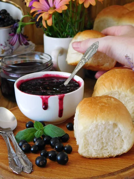 Golden buns and berry jam. Female hand is taking a bun