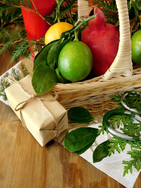 A wicker basket filled with fruits surrounded by present boxes and tools for gift wrapping