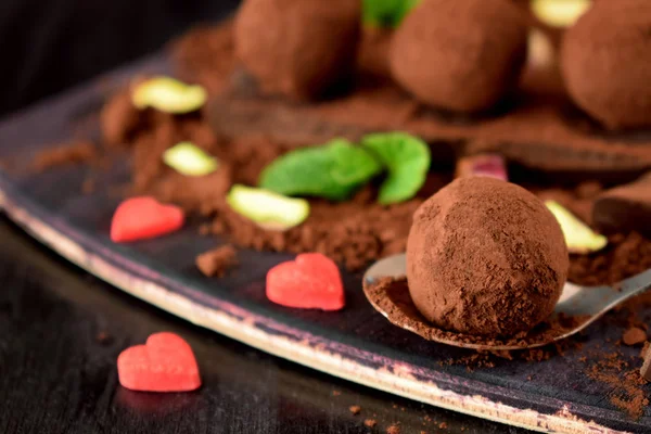 Chocolate truffles covered with cacao powder and red sugar hearts are scattered around