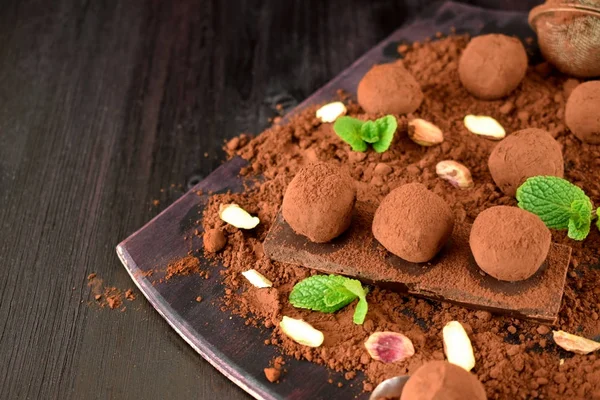 Chocolate truffles covered with cacao powder, pistachio nuts, chocolate and mint