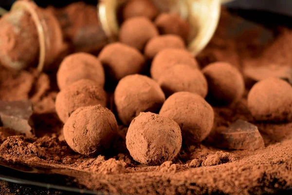 Chocolate truffles covered with cacao powder on a black plate