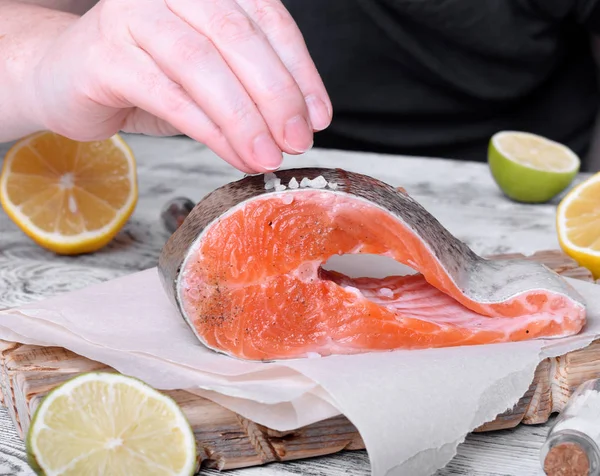 The cook is putting some sea salt on the red fish steak