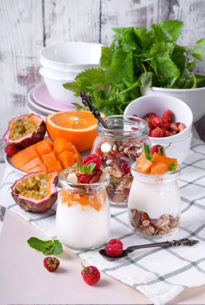 Natural yogurt, granola and mashed passion fruit and mango layered in a glass jar. Breakfast idea