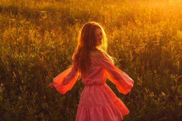 Dançando sorrindo menina bonita em vestido rosa no campo, sol — Fotografia de Stock