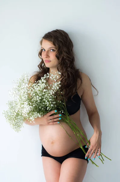 Zwangere vrouw met boeket bloemen in handen — Stockfoto
