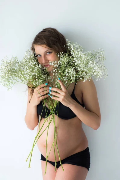Zwangere vrouw met boeket bloemen in handen — Stockfoto