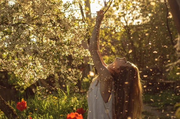 Meisje in witte jurk zitten tussen bloemen en pluis — Stockfoto