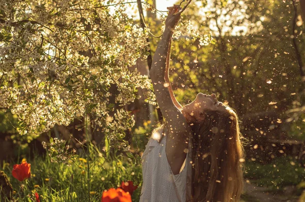 Meisje in witte jurk zitten tussen bloemen en pluis — Stockfoto