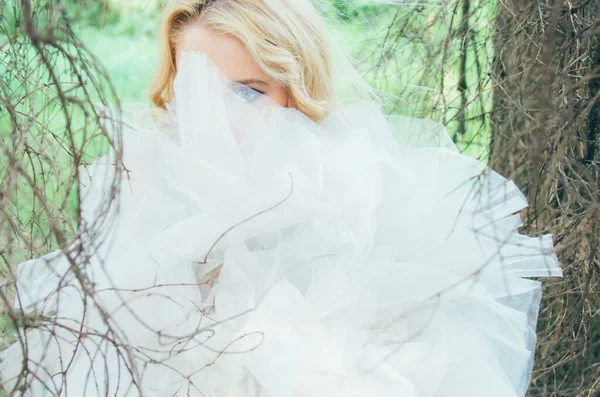 Retrato de noiva loira jovem na floresta através de ramos e vei — Fotografia de Stock