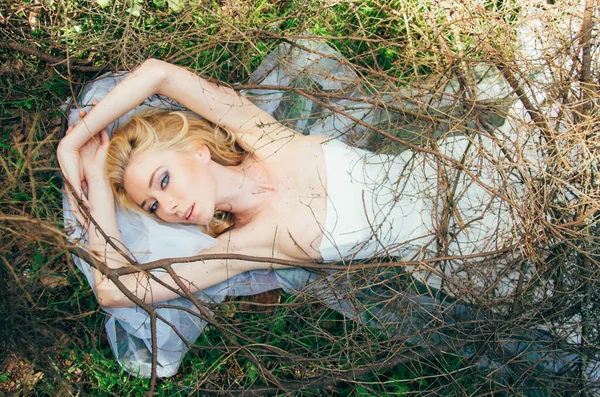 Ritratto di giovane sposa bionda con velo che giace sulla terra sotto — Foto Stock