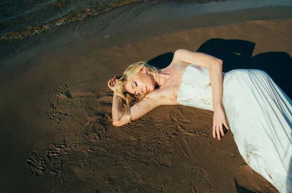 Portrét mladé blond nevěsty leží na písku mezi vodou — Stock fotografie