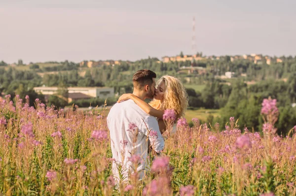 Молодой человек обнимает и целует свою девушку в поле — стоковое фото