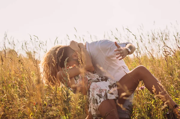 Молодий чоловік обіймає і цілує свою дівчину в полі — стокове фото
