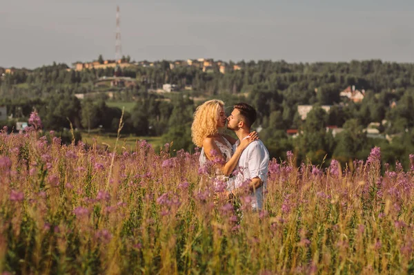 Jovem abraçando e beijando sua namorada no campo — Fotografia de Stock