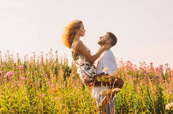 Joven hombre llevar a su novia en las manos en el campo —  Fotos de Stock