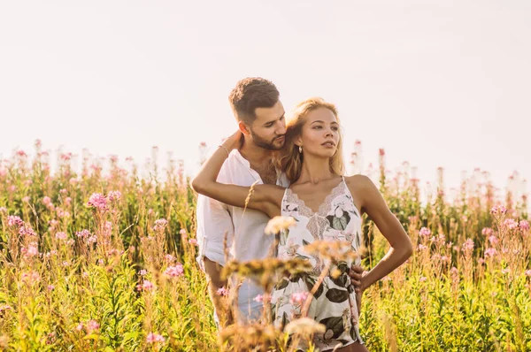 Mladý muž objímající svou přítelkyni v poli — Stock fotografie