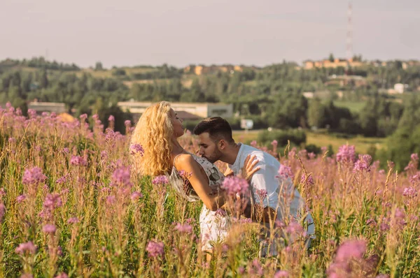 Молодой человек обнимает и целует свою девушку в поле — стоковое фото