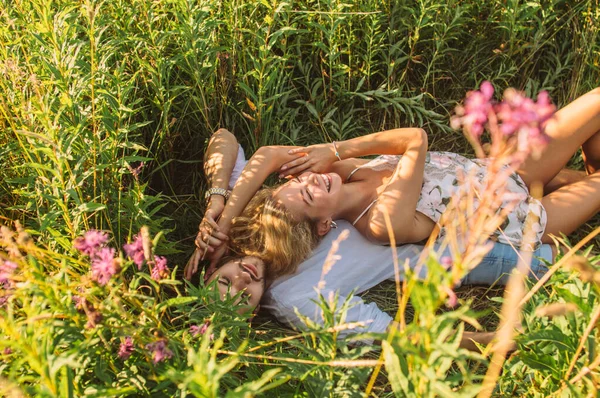 Young woman lies on her boyfriend and fools around in the field — Stockfoto