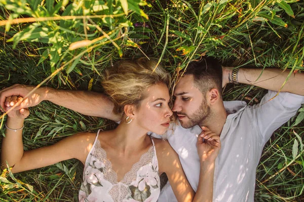 Young man and woman lies together in the field — Stock Photo, Image