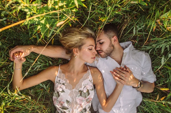 Young man and woman lies together in the field — ストック写真