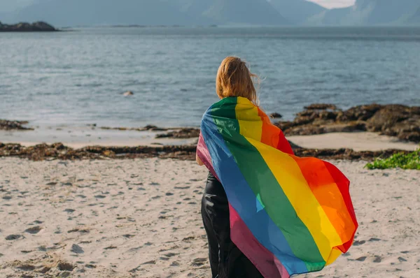 Chica rubia joven cubierta con bandera LGBTQI caminando en el día a día — Foto de Stock