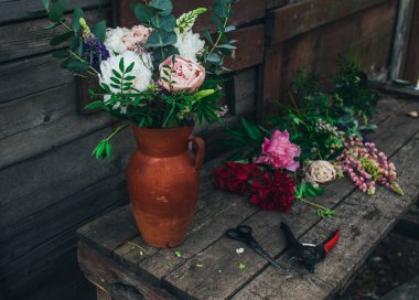 Kavanozda pembe ve beyaz şakayıklar olan bir buket.