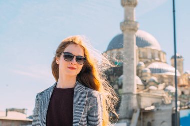 Sarışın güzel kız, eski İstanbul kentinde Süleyman Camii ve İstanbul Boğazı manzaralı duruyor