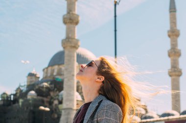 Sarışın güzel kız, eski İstanbul kentinde Süleyman Camii ve İstanbul Boğazı manzaralı duruyor