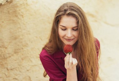 Mor elbiseli güzel sarışın kız doğada taze çilek yiyor.