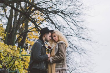 Halk parkında yürüyen ve kucaklaşan çiftler, bir sürü sarı ağaçla sonbahar mevsimi.