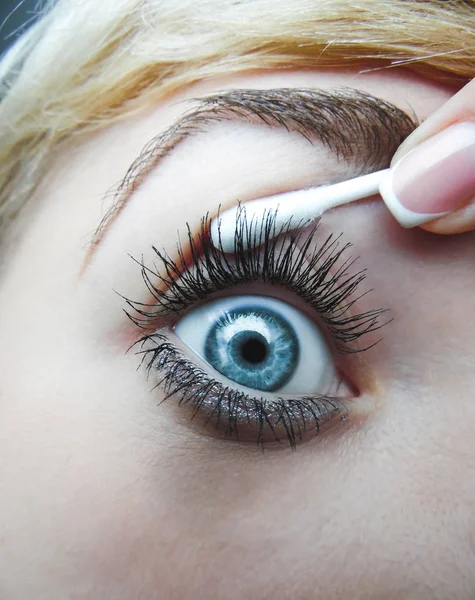 Kvinnors ögat dras med en bomull svabb och finger fransk manikyr. makro — Stockfoto