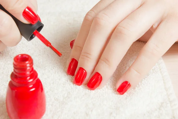 Manicura - Hermosas uñas de mujer cuidadas con esmalte de uñas rojo sobre una toalla blanca suave . — Foto de Stock