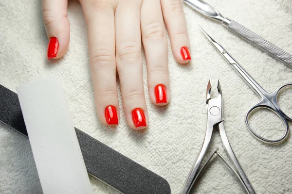 Uñas rojas cuidadas con implementos de uñas en toalla blanca — Foto de Stock