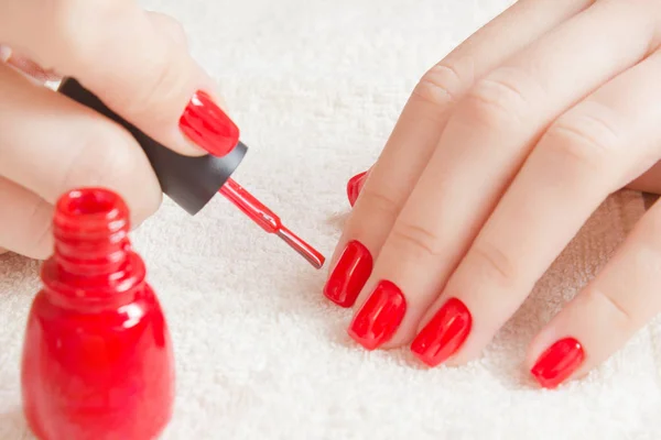 Manicura: hermosas uñas de mujer cuidadas con esmalte de uñas rojo sobre una toalla blanca suave . — Foto de Stock