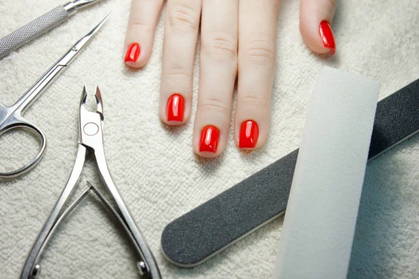 Uñas rojas cuidadas con implementos de uñas en toalla blanca — Foto de Stock