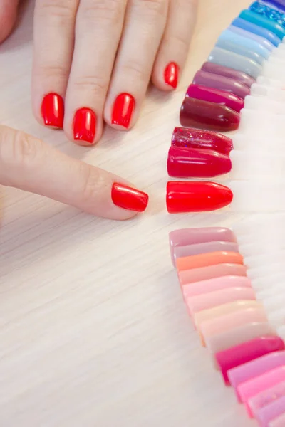 Üstten Görünüm kadın sarı renk shellac oje seçer. Tırnak teknisyeni tırnak Hizmetleri renk paletinin güzellik salonunda gösterir..
