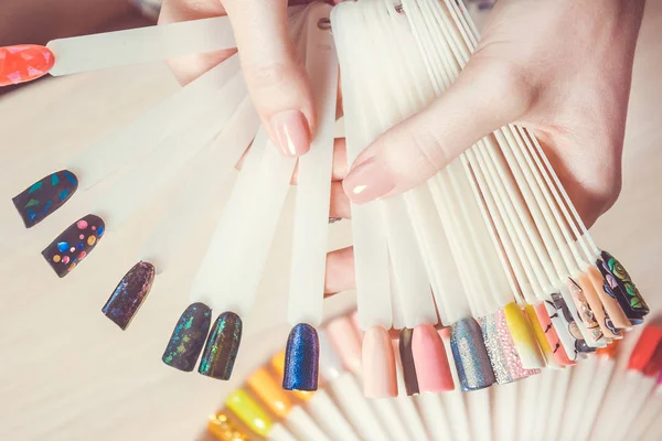 Bovenaanzicht vrouw selecteert gele kleur schellak nagellak. Nagel technicus toont het kleurenpalet van de diensten van de nagel in de beauty salon. — Stockfoto