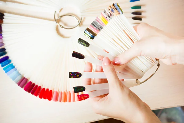Top vue femme sélectionne la couleur jaune vernis à ongles gomme laquée.Nail technicien montre la palette de couleurs des services ongles dans le salon de beauté . — Photo