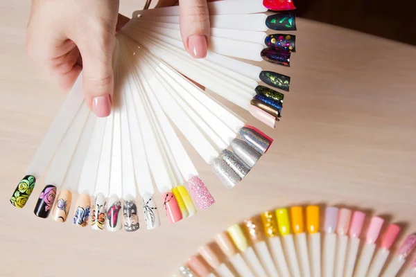 Bovenaanzicht vrouw selecteert gele kleur schellak nagellak. Nagel technicus toont het kleurenpalet van de diensten van de nagel in de beauty salon. — Stockfoto