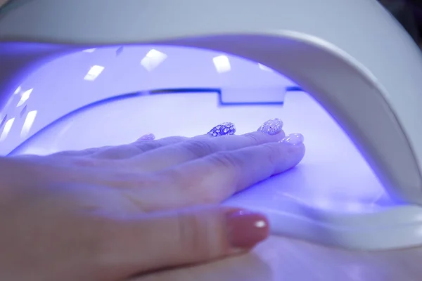 Professionnel ultraviolet ongles manucure lampe gel de séchage polissage sur les femmes main dans un salon de beauté — Photo