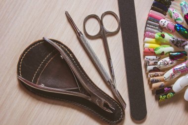 Beyaz ahşap zemin üzerinde çivi paletle makası, törpü ve makası manikür