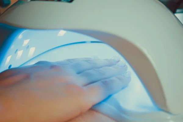 Профессиональный ультрафиолетовый маникюр для ногтей лампы сушки оболочки гель полировка на женской руке в салоне красоты — стоковое фото