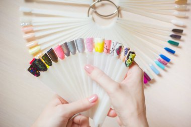 Üstten Görünüm kadın sarı renk shellac oje seçer. Tırnak teknisyeni tırnak Hizmetleri renk paletinin güzellik salonunda gösterir..