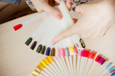 Üstten Görünüm kadın sarı renk shellac oje seçer. Tırnak teknisyeni tırnak Hizmetleri renk paletinin güzellik salonunda gösterir..