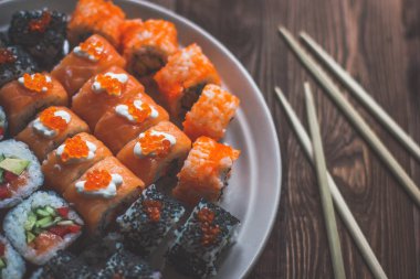 Sushi maki Rolls ile Chopsticks üzerinde bir ahşap tabağı ile wasabi-görüntülenen Above Izole gri ahşap arka plan.