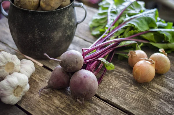 Bir eski pot patates soğan sarımsak pancar eski tahta arka plan üzerinde