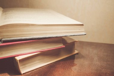 Renkli kapaklı kitap yığını. Kitaplık veya kitapçı. Kitap veya ders kitapları. Ön planda açık kitap.