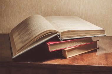 Renkli kapaklı kitap yığını. Kitaplık veya kitapçı. Kitap veya ders kitapları. Ön planda açık kitap.