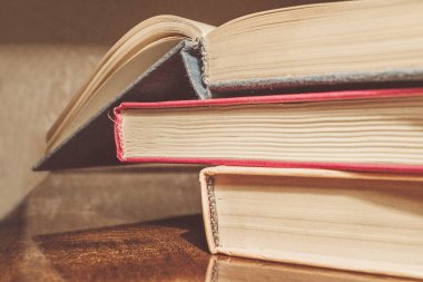 Renkli kapaklı kitap yığını. Kitaplık veya kitapçı. Kitap veya ders kitapları. Ön planda açık kitap.