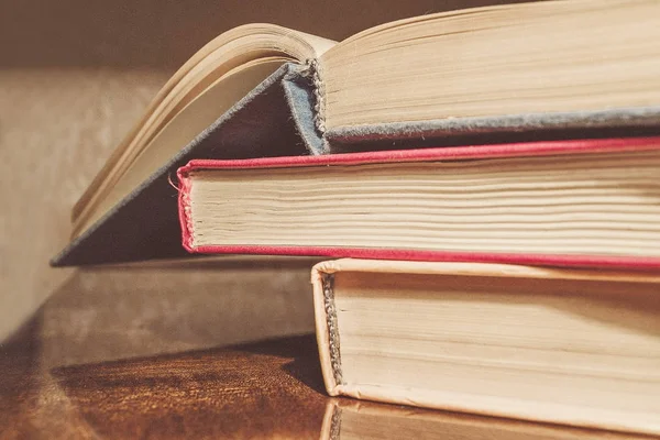 Renkli kapaklı kitap yığını. Kitaplık veya kitapçı. Kitap veya ders kitapları. Ön planda açık kitap.